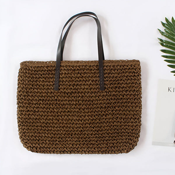 Sac à main marron en paille avec anses en cuir noir. Accessoire de mode estival, style décontracté et bohème. Idéal pour la plage ou le shopping.