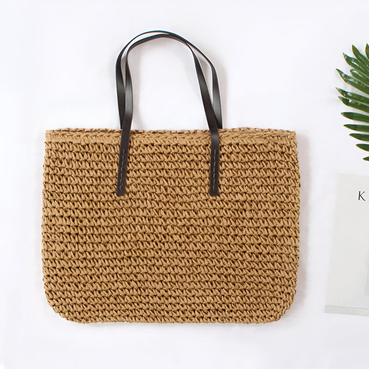 Sac de plage tressé vert olive avec anses en cuir marron foncé, idéal pour l'été. Accessoire de mode féminin, léger et pratique.