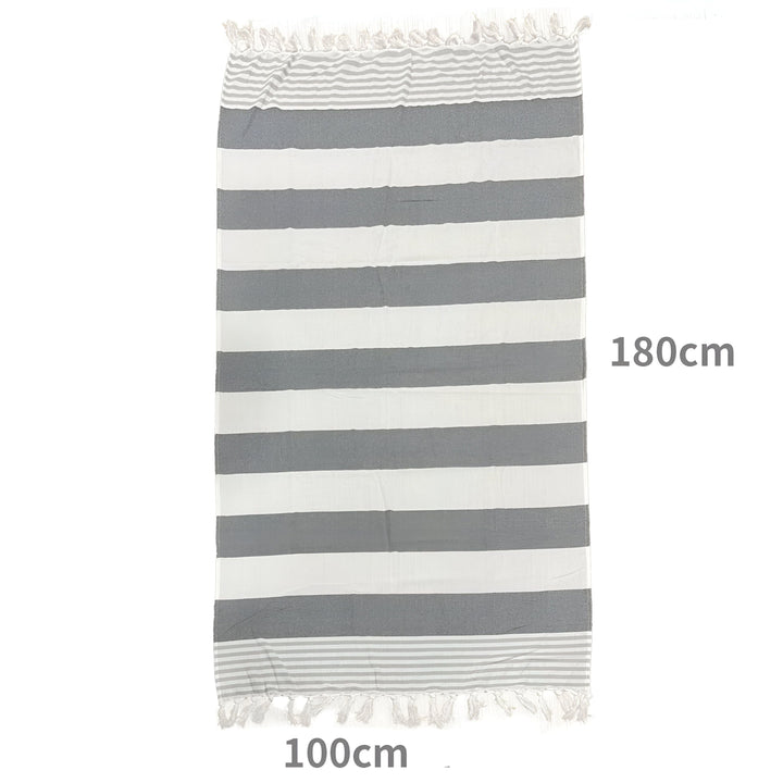 Serviette de plage turque bleue et blanche rayée, pliée avec des franges blanches, sur un fond blanc. Idéal pour la plage, la piscine ou le spa. Douce, légère et à séchage rapide.