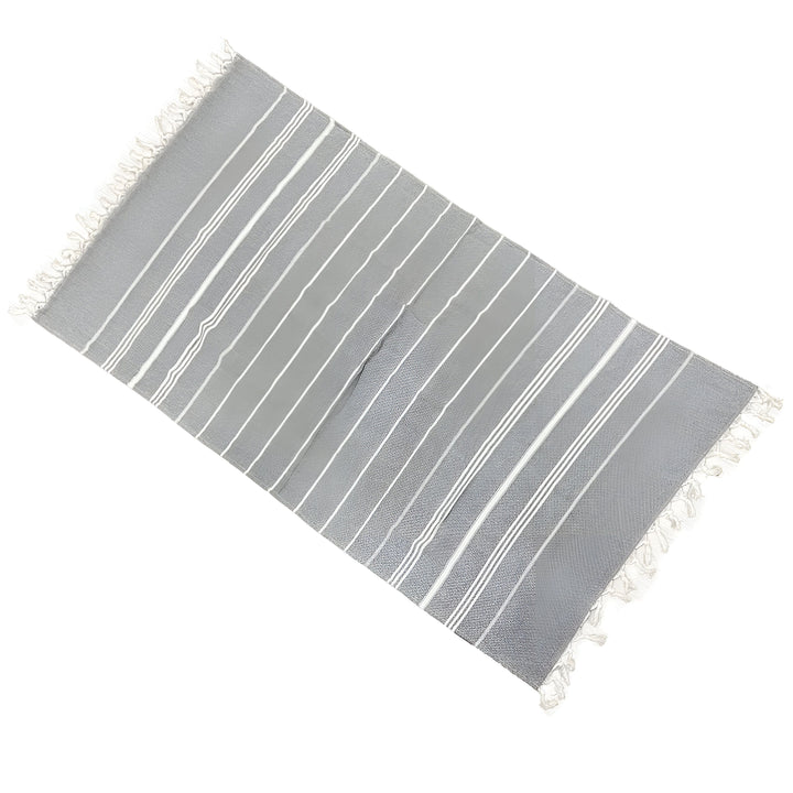 Serviette de plage rayée bleue et blanche avec des franges, vue de dessus, idéale pour l'été et les vacances. Textile doux en coton, accessoire de bain pratique.