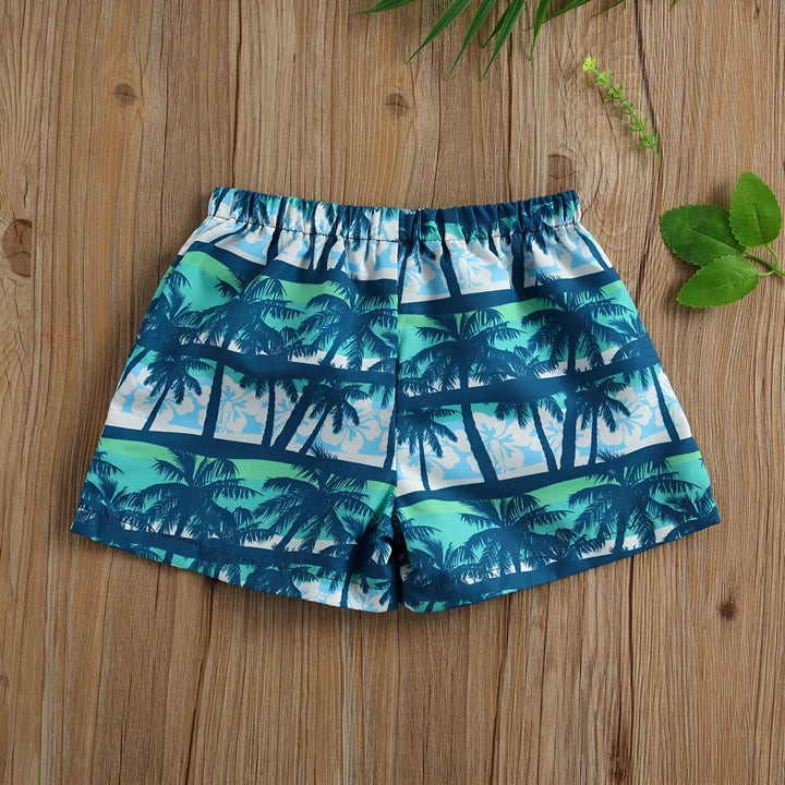 Short de bain pour enfant, motif palmiers bleus et verts, cordon blanc à la taille, sur fond bois clair. Idéal pour la plage ou la piscine. Vêtement d'été enfant.