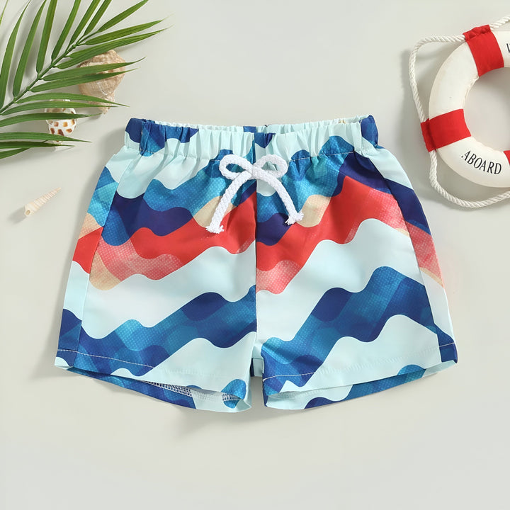 Short de bain enfant, motif vague bleu et rouge, cordon blanc à la taille. Idéal pour la plage ou la piscine, style marin et estival.