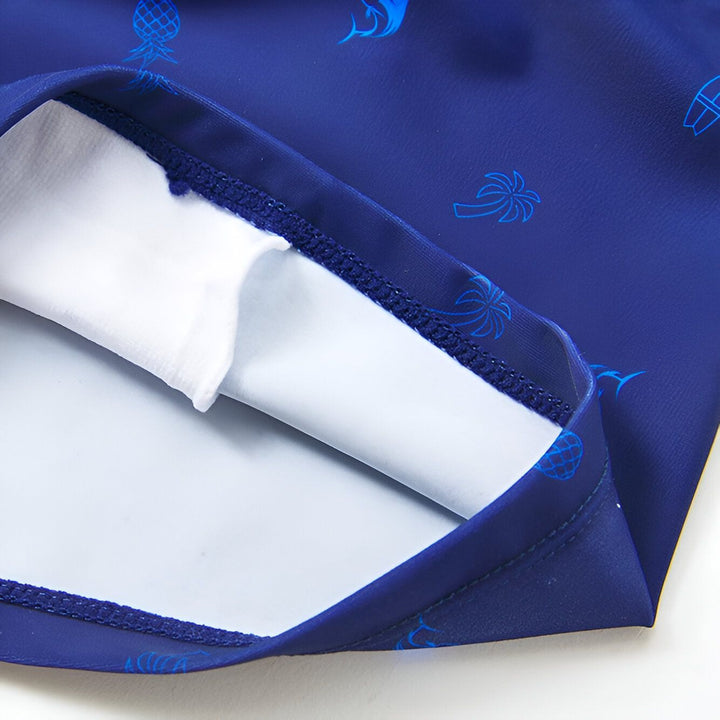 Image d'un slip de bain noir, coquillage, étoile de mer et feuille tropicale sur fond blanc. Idéal pour la plage et la piscine en été.