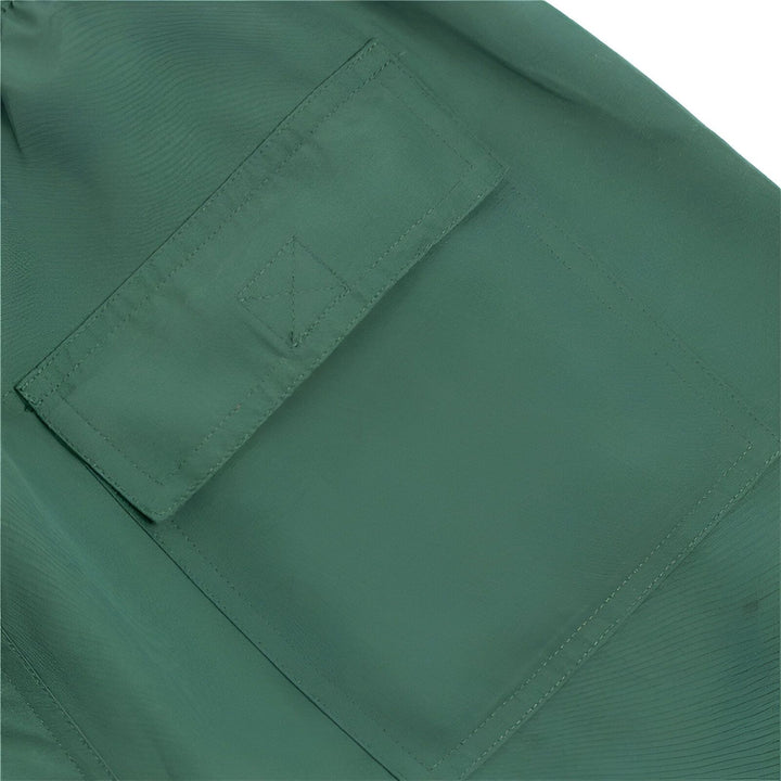 Gros plan sur le détail d'un short cargo noir, mettant en évidence les poches et leurs logos carrés blancs distinctifs.