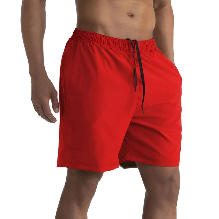 Homme portant un short de bain bleu marine avec cordon de serrage, mains dans les poches. Vêtement d'été, maillot de bain pour homme, mode masculine décontractée.
