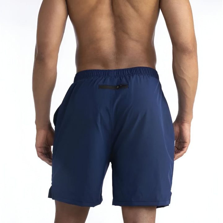 Un homme vu de dos porte un short de sport rouge. Il met une carte dans la poche arrière zippée de son short. Idéal pour courir.