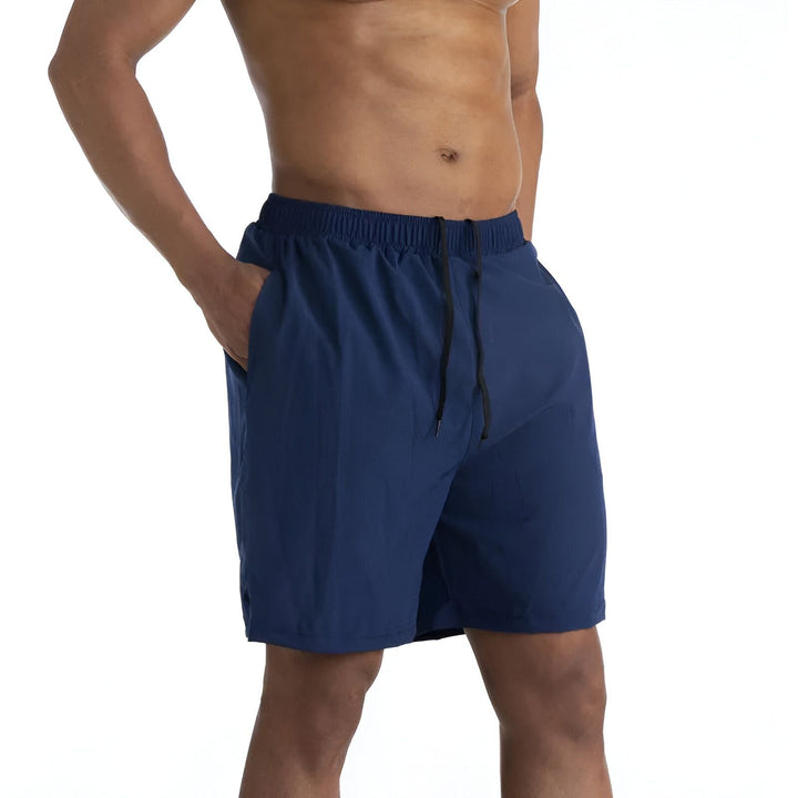 Homme torse nu portant un short de bain bleu marine avec cordon noir et poche.