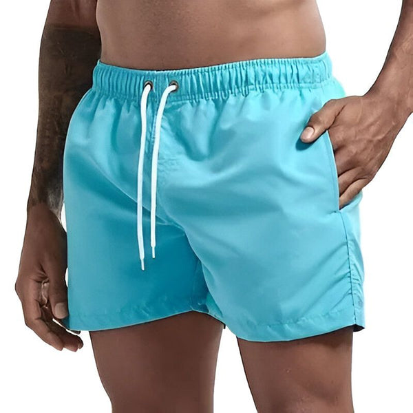 Gros plan d'un short de bain turquoise avec une poche en filet blanc, mettant en évidence la texture du tissu et les détails de la couture.