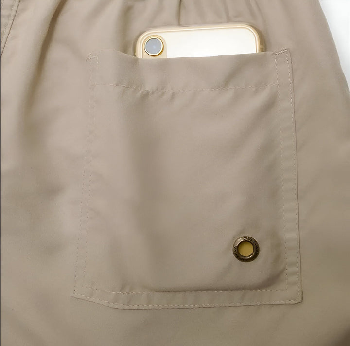 Vue rapprochée d'un short de bain turquoise avec une doublure en filet blanc et des poches. La taille élastique est agrémentée d'un cordon de serrage.