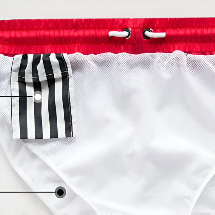 Homme torse nu portant un short de bain à rayures noires et blanches avec une ceinture rouge et des cordons blancs.
