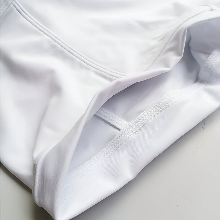 Homme de dos portant un caleçon de bain noir avec des motifs Mondrian (blanc, rouge, jaune). Gros plan sur son dos musclé. Photographie de mode masculine.