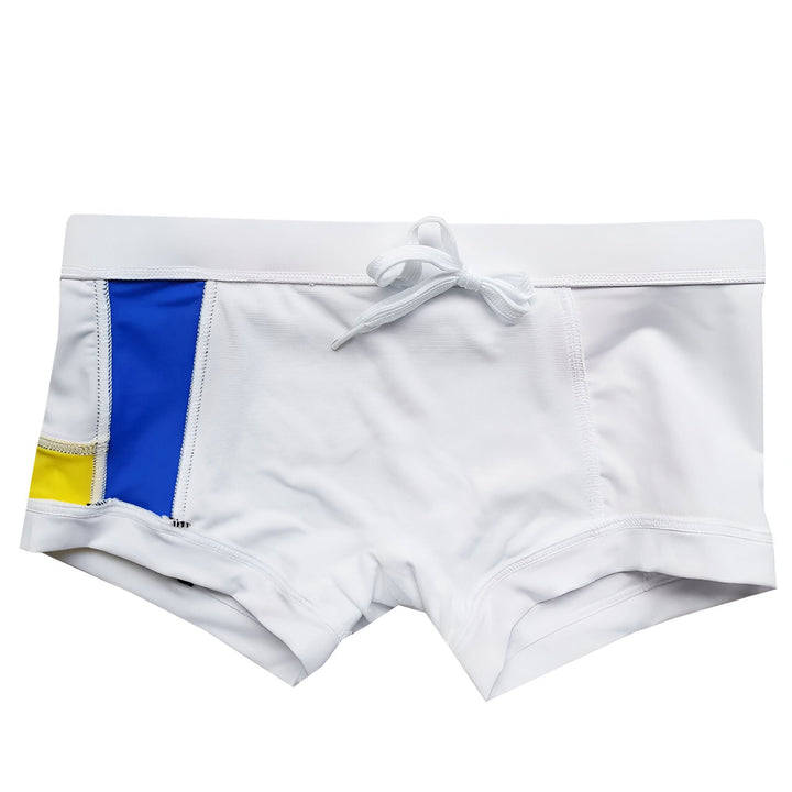 Homme torse nu portant un caleçon blanc avec des motifs Mondrian (bleu, jaune, rouge). On voit une prothèse de pénis à côté. Sous-vêtements masculins originaux. Amélioration de la silhouette masculine.