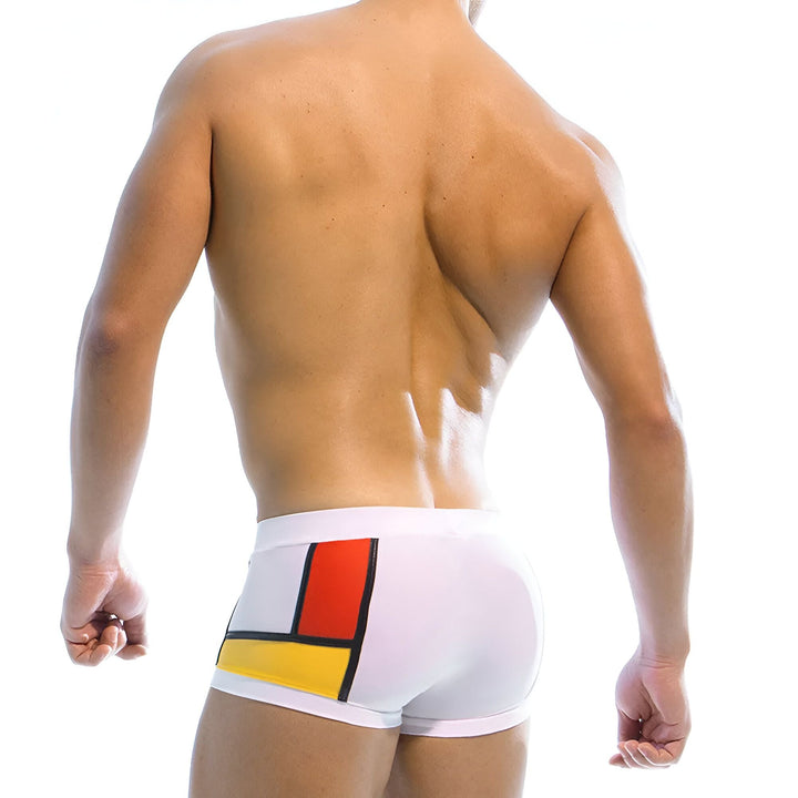 Homme musclé torse nu portant un slip de bain noir avec un design coloré de style Mondrian sur le côté. Coussinets amovibles inclus.