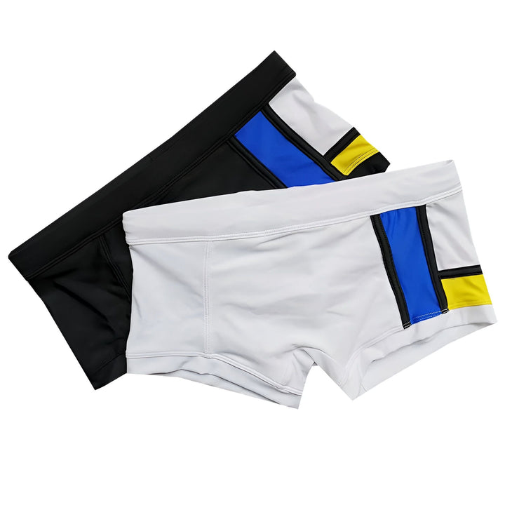 Détail d'un maillot de bain blanc avec des empiècements bleu et jaune séparés par des bandes noires. Design moderne et épuré, parfait pour l'été.