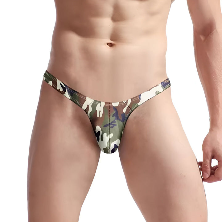 Homme torse nu portant un string camouflage vert, marron et blanc. Sous-vêtement masculin, mode masculine, tissu imprimé camouflage, corps athlétique.