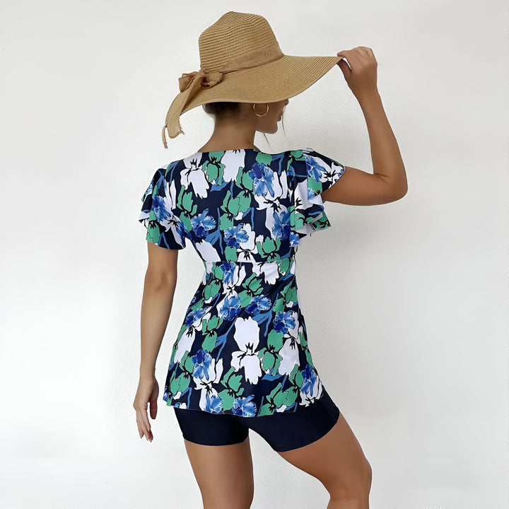 Vue arrière d'une femme portant un maillot de bain fleuri bleu et vert et un chapeau de paille beige. Mode estivale, vêtements de plage, protection solaire.